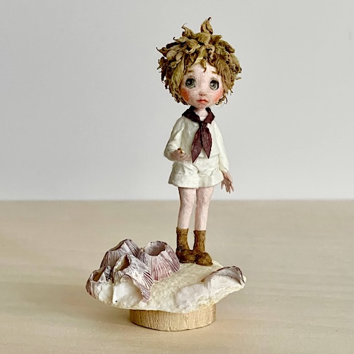 貝殻の上に佇む和紙人形の完成作品。静かな旅を思わせる物語性のある造形。(正面)