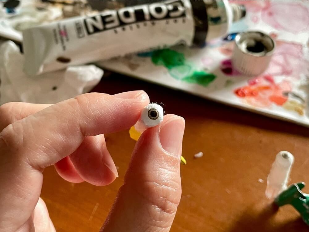 和紙人形の目のパーツを作る工程。細かな造形と彩色のわかる手元のアップ。