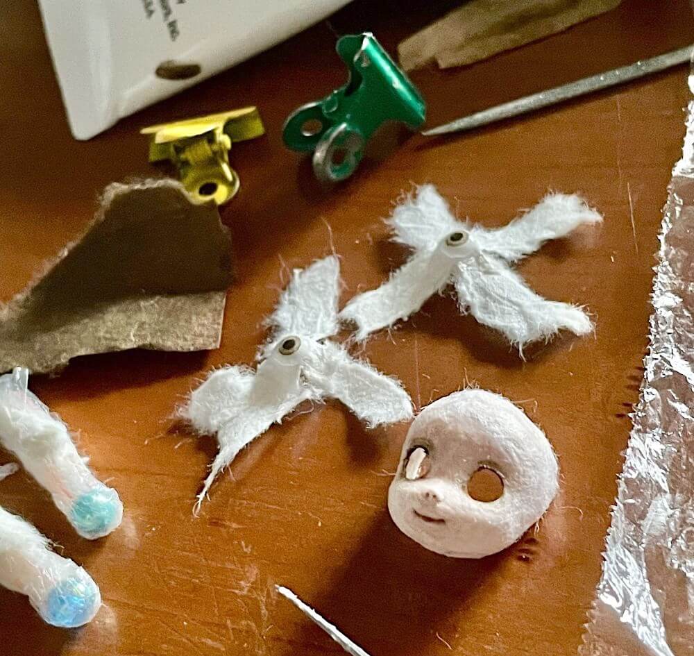 少年の頭部、顔パーツと眼球、まつ毛用の和紙を並べている工程写真。