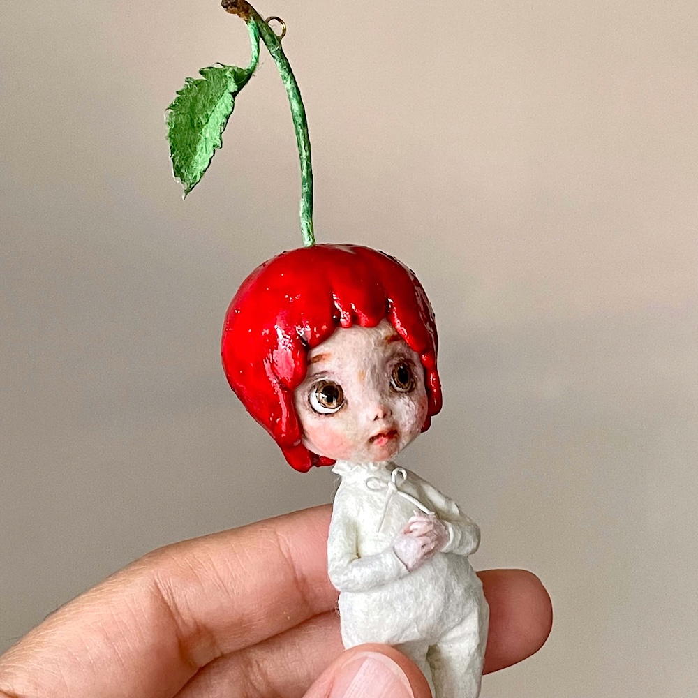 赤いさくらんぼの頭部と小さな身体を持つ和紙人形、顔・上半身アップ。Cherry Blossom Girl