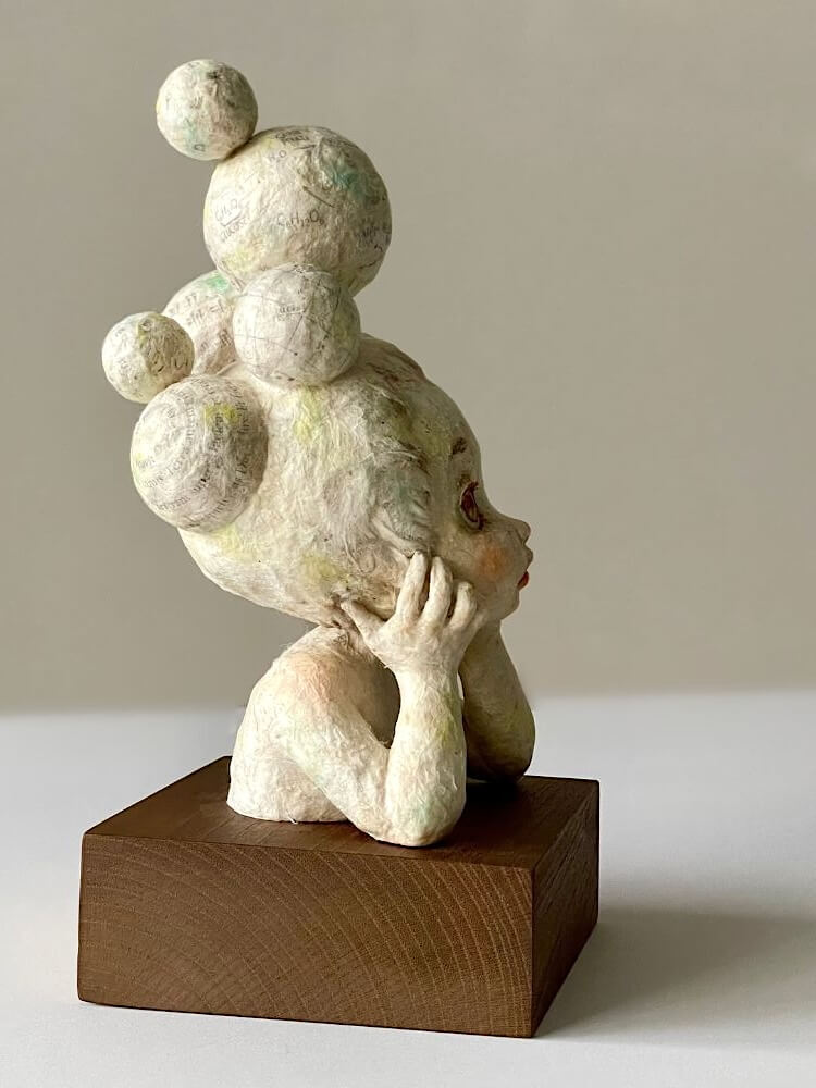木製台座に佇むロクタ紙の創作人形「頭の中に浮かぶもの」の完成作品