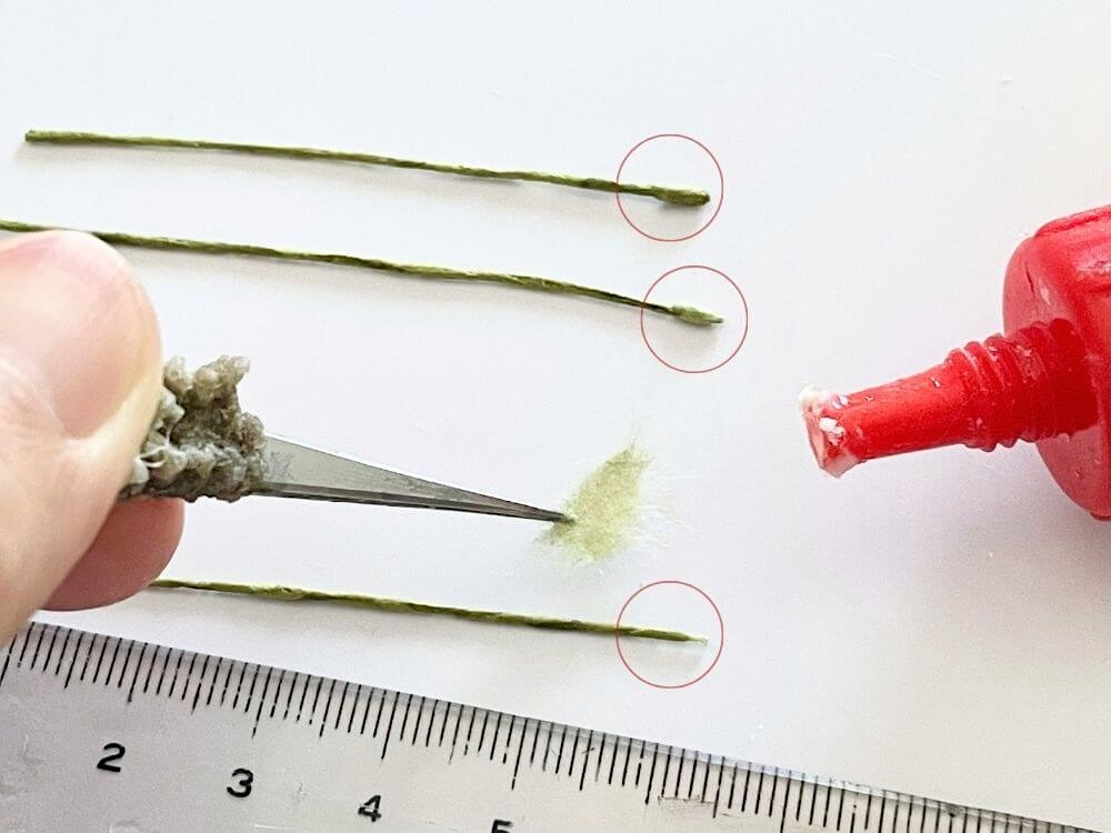 和紙を巻いた細い茎の先端に小さな紙片を巻きつけて鼻の土台を作る工程